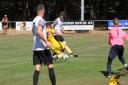 UEA defender in yellow kit makes desperate attempt to block a shot from Beccles Town forward.