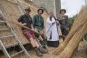 Rev Mark Bee with the team of thatcher's up the scaffold of the 15th-century church