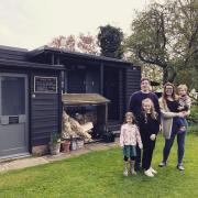Kevin, 39 (left) and Anissa, 38 (right) pictured with their children in front of the Honesty Shop on their Wildings Elms Meadow site in South Norfolk