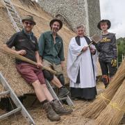 Rev Mark Bee with the team of thatcher's up the scaffold of the 15th-century church