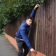 The village where every centimetre matters - our reporter Bruno Brown measuring the fence at the centre of a dispute at Highland Drive