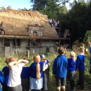 Students up the scaffold of the 15th century Ringsfield Church which is being rethatched
